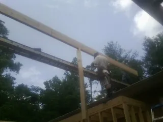 Carpenter setting a ridge beam over a new addition frame — Ice Dam Removal by Roofing Brothers in Wampsville