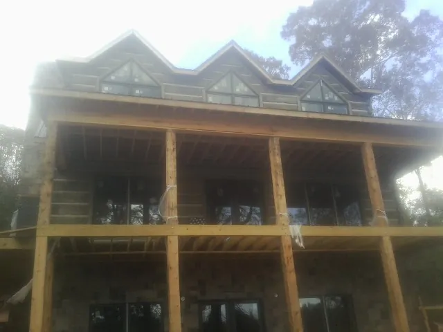 Dormers and porch framing on a large log home under construction — Roof Coating work by our crew in Wampsville