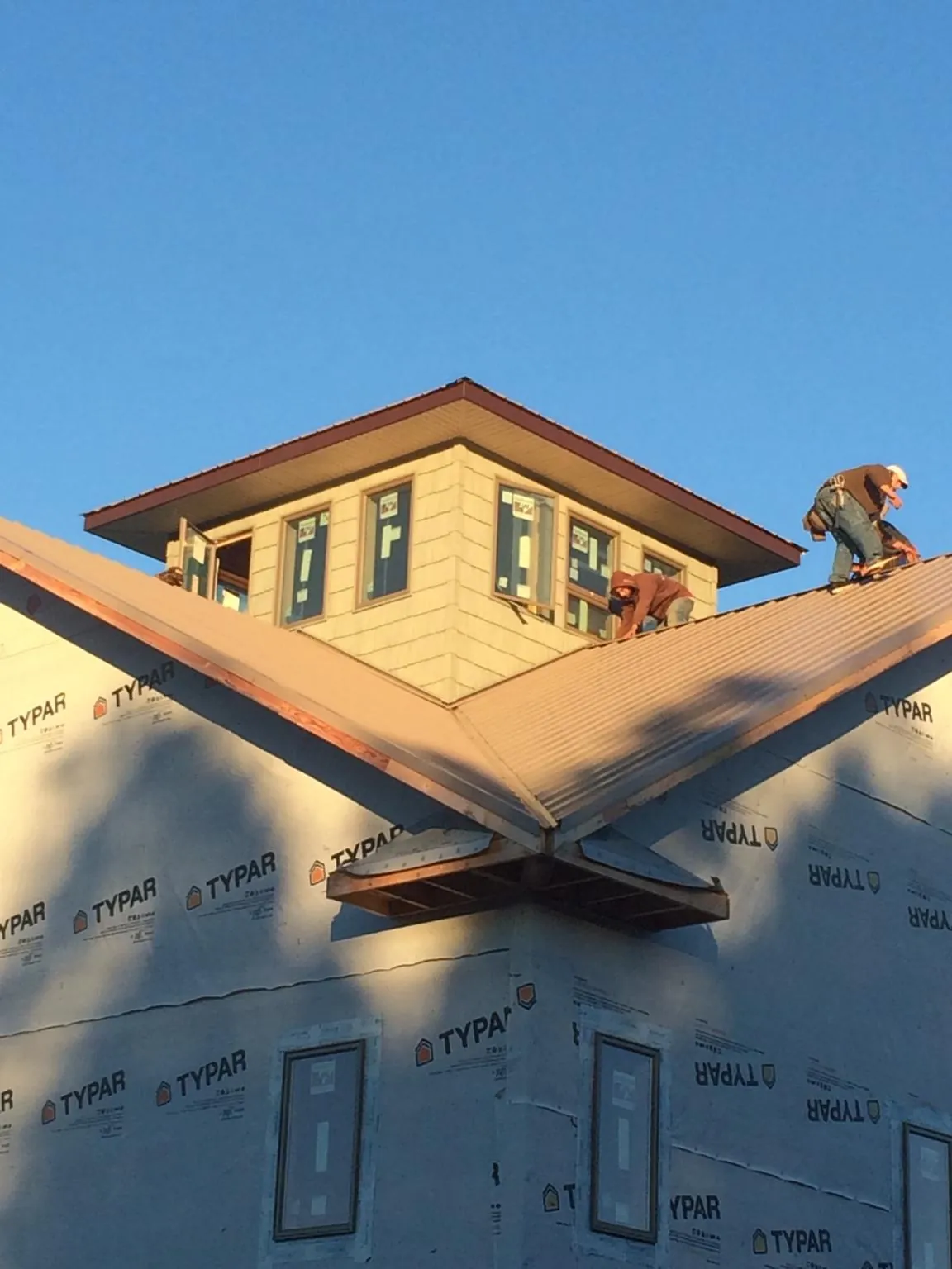 Roofers working around a rooftop cupola on a new metal roof at sunset — Roof Waterproofing in Wampsville by Roofing Brothers